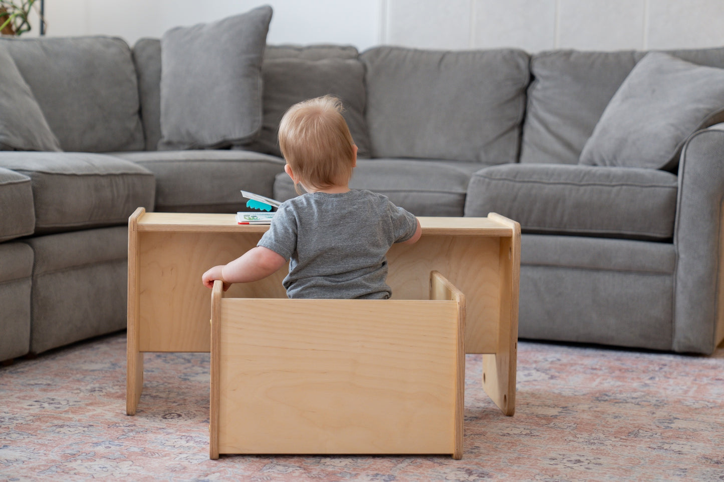 Child playing with wooden furniture in a living room