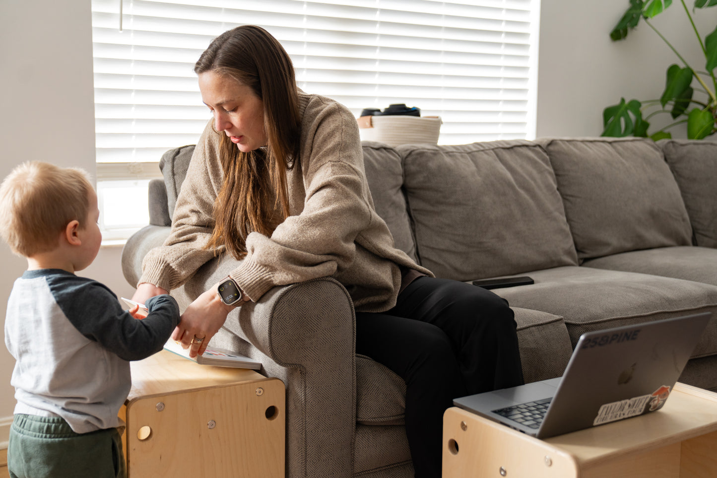 Woman sitting on a couch with a child in a living room setting.