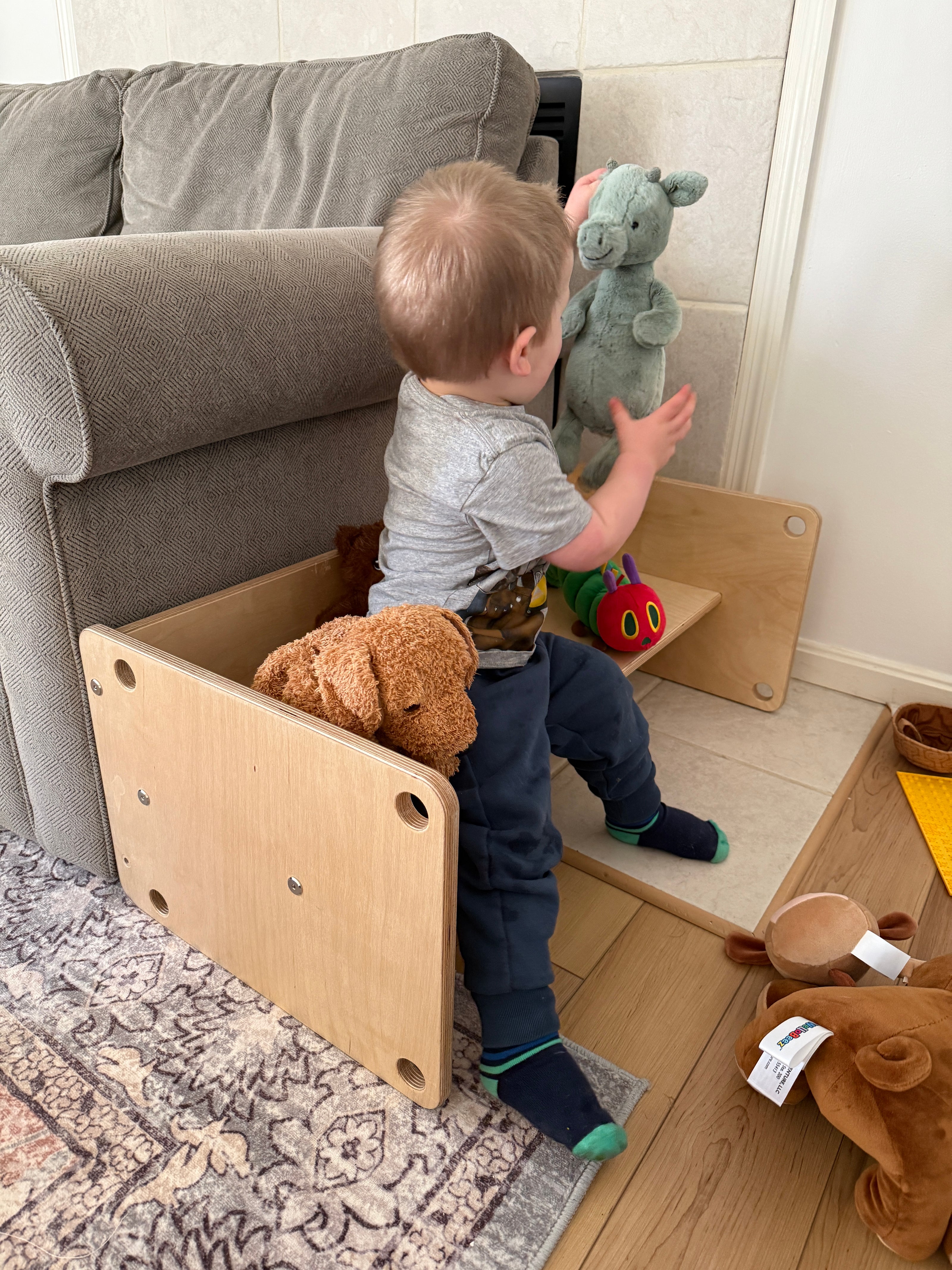 Toddler playing with stuffed animals on wooden kids bench in living room no playroom needed