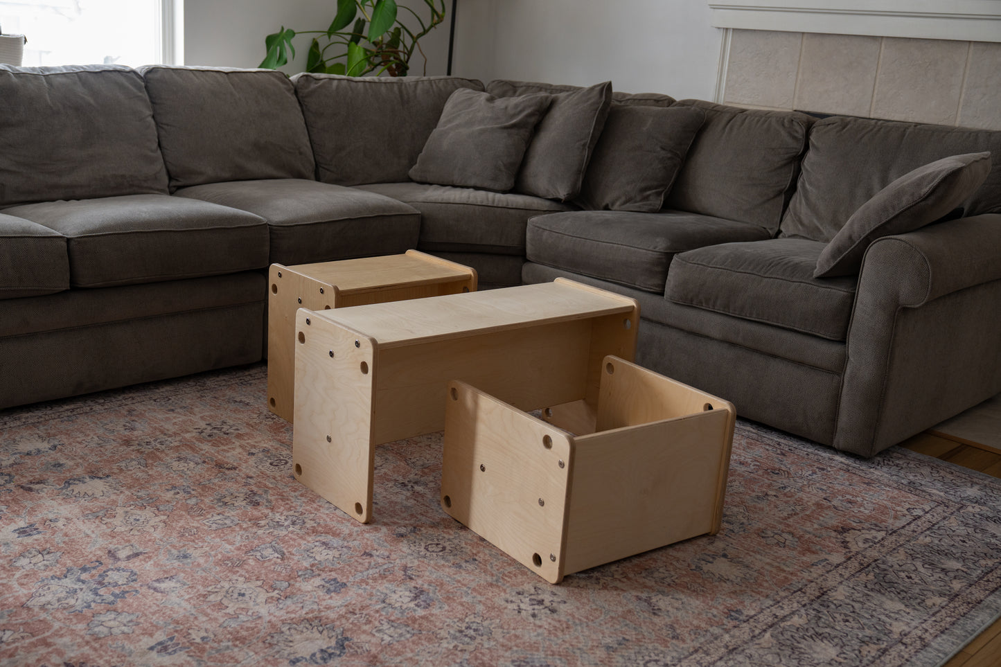 gray sectional sofa with wooden coffee table  and toddler chairs on a patterned rug